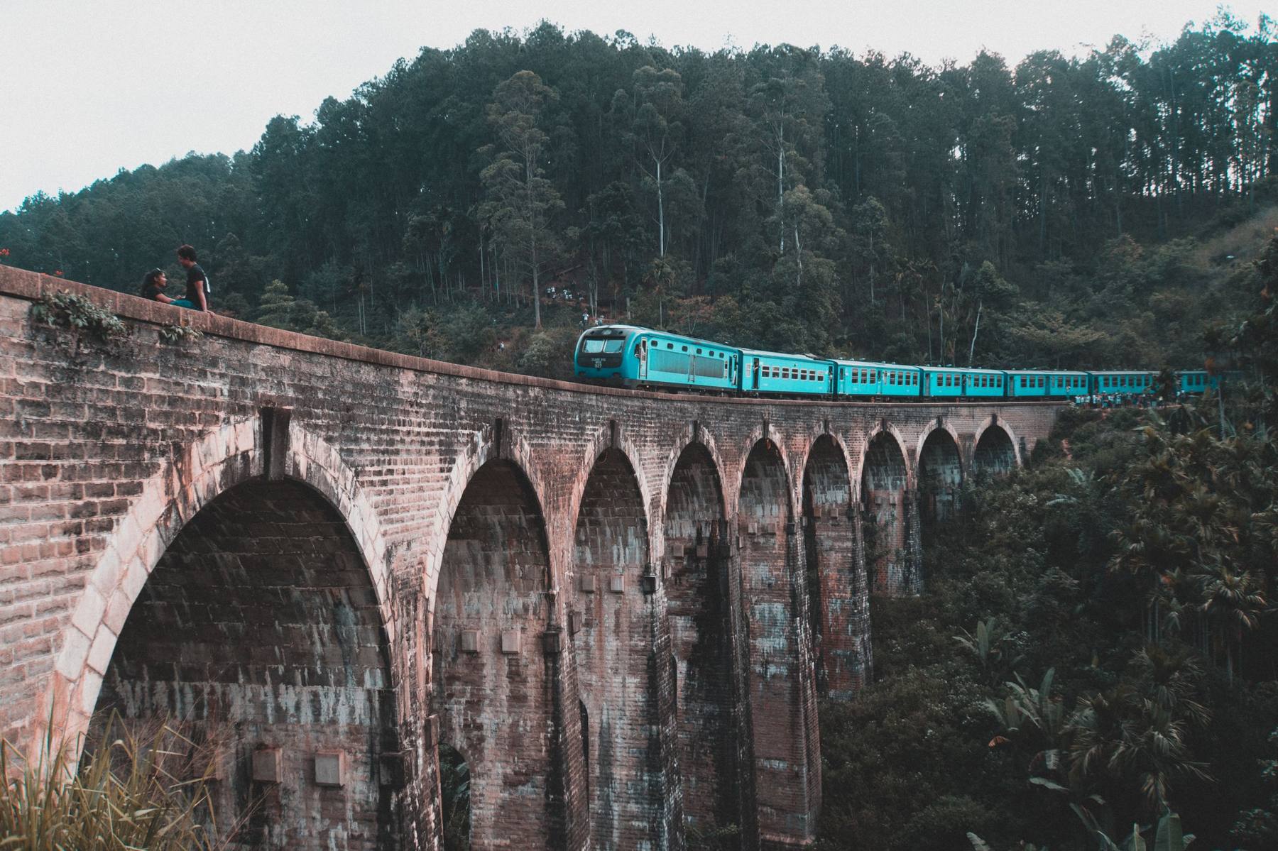Nine Arch Bridge and a blue train crossing misty hill country